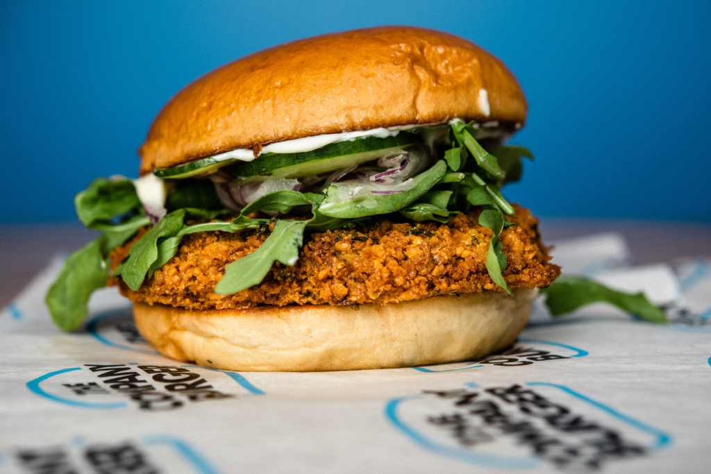 Falafal Burger for vegetarians, dressed in lemon mayo, harissa, cucumber, and arugula.